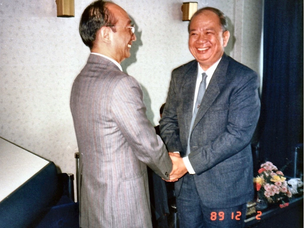 1989年12月2日合艾签署大典贵宾厅内，马共中央总书记陈平（右）在纪念册签名留念后与与会嘉宾（左）亲切握手