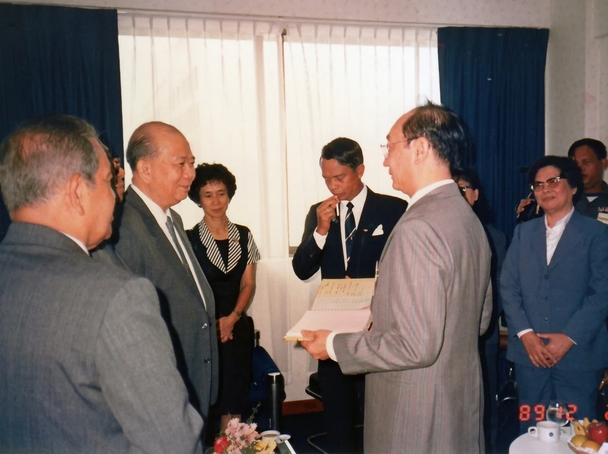 1989年12月2日合艾贵宾厅内，拉昔·迈丁（左一）、阿都拉·西迪（左二）、陈平（左三）与随团女翻译（左四）、吉迪将军（中）、手捧纪念册的与会嘉宾（右二）及陈再润（右一）交谈留影