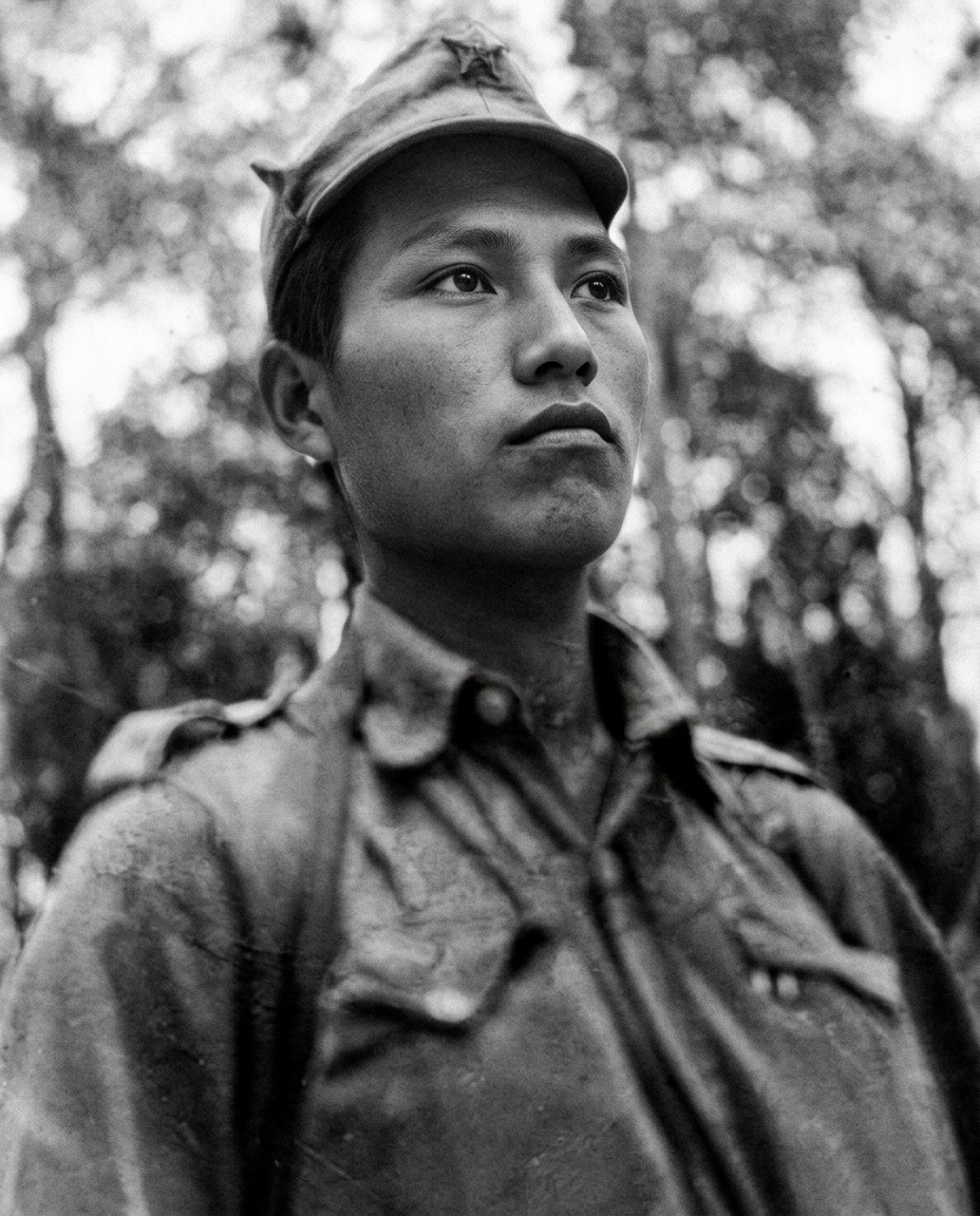 1952年10月抗英民族解放战争初期，头戴五角星军帽、身着丛林军装的马来亚民族解放军战士坤龙肖像（照片背面墨书“一九五二年十月 坤龙”）。