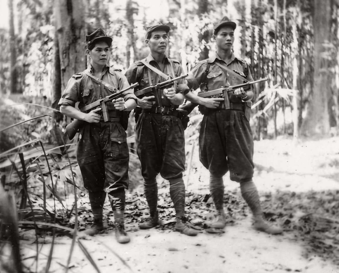 1950年代抗英民族解放战争期间，三名头戴五角星军帽、裹扎绑腿并手持美制汤姆逊冲锋枪（Thompson SMG）的马来亚民族解放军战斗骨干在密林合影。