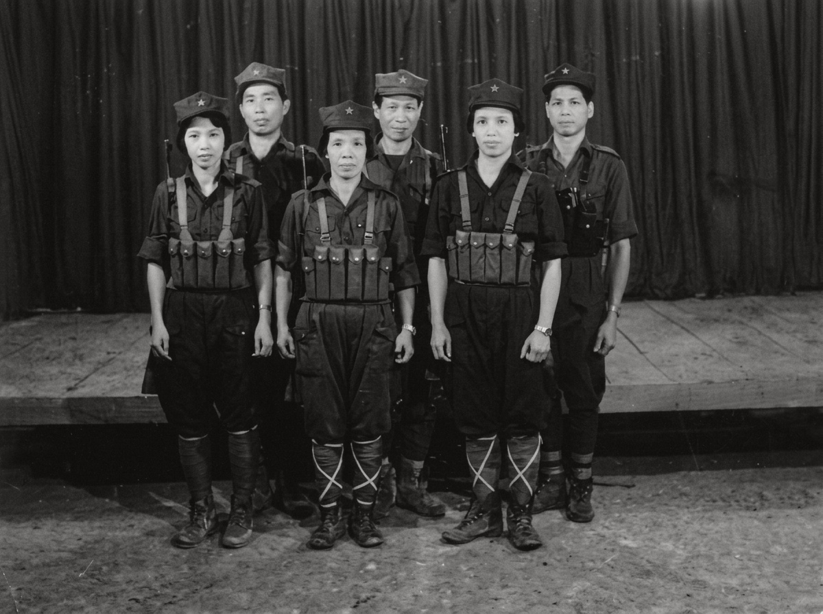 1986年元旦马来亚人民军（MPA）男女指战员于泰马边境“坚持营房”木制舞台前全副武装合影，胸前佩戴标准弹匣袋并裹扎绑腿。