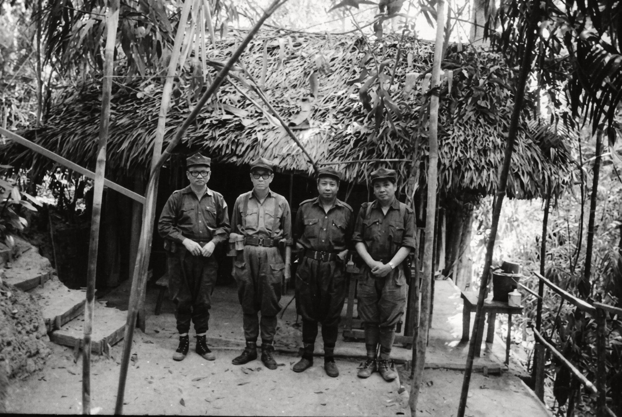 1977年马共中央与北马局四位领导人前往密林疗养营房探望慰问第十支队领导人阿布·沙玛（Abu Samah）后，于竹木茅屋前合影。