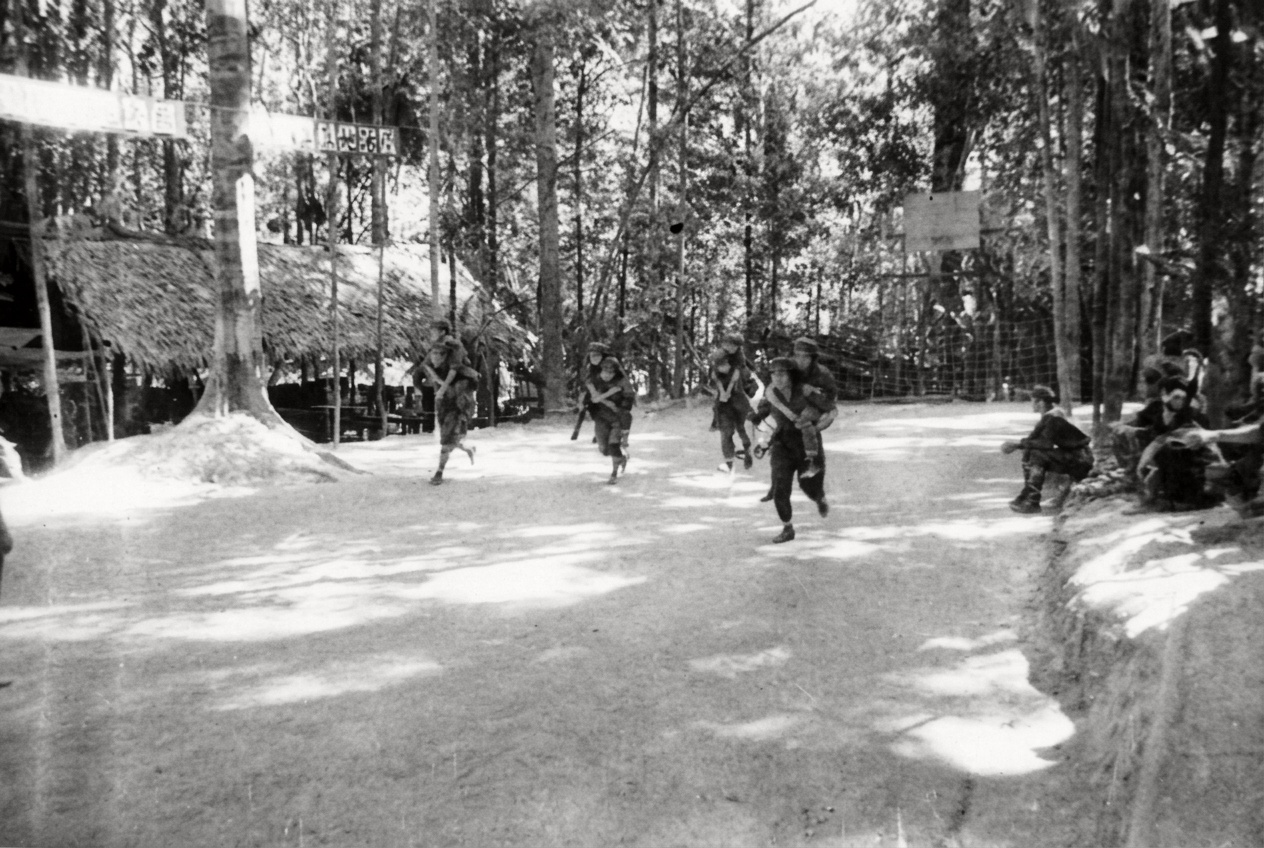 1967年密林营地“军事技术与战场救伤”演练现场，战地卫生员与突击队员背负伤员在丛林操场上快速冲刺转移。