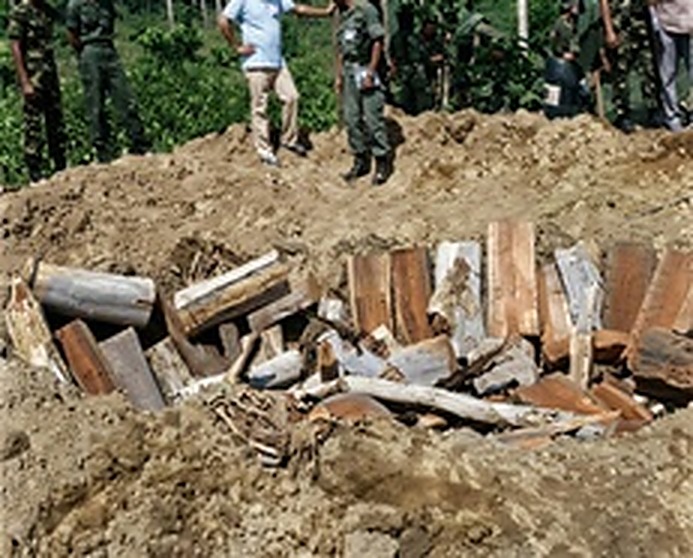 爆破坑内景：人民军工程人员将成箱弹药、地雷壳体与木材层层叠放在大型土坑中，准备实施集中引爆与焚毁。