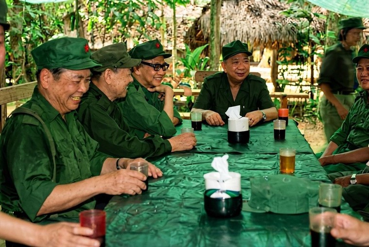 陈平（居中正坐者）在密林营地团聚茶叙席间，与并肩战斗数十载的老一辈支队干部围坐长桌旁举杯共庆、畅叙战友情谊。