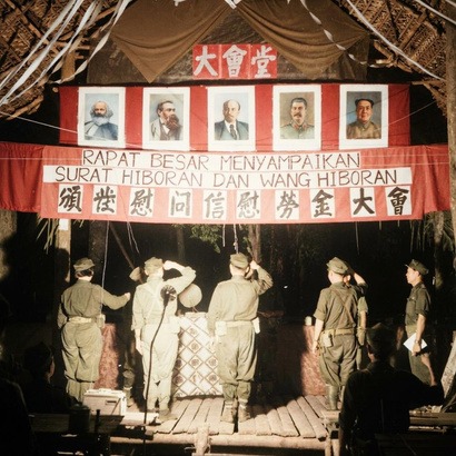 马来亚民族解放军第十二支队军营隆重举行“颁恤烈属慰劳金大会”历史实照（会场横幅高悬马恩列斯毛画像与革命红旗）